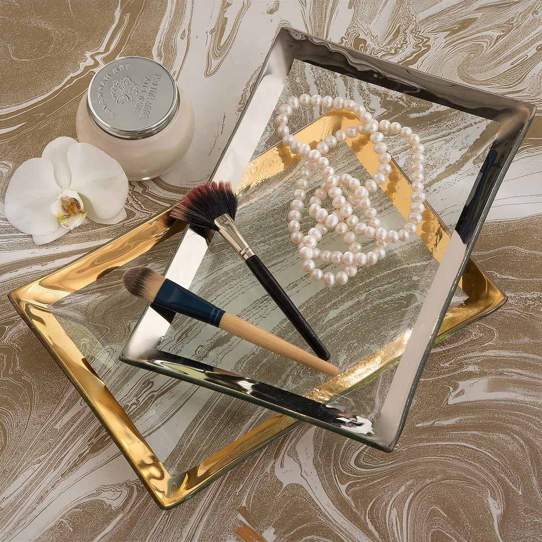 Small rectangular trays with a platinum and 24k gold band with pearls and makeup brushes.